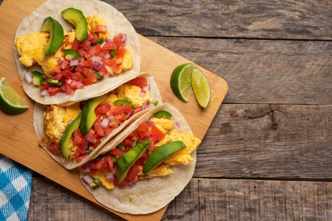 Traditional breakfast egg tacos with flour tortilla and fresh sauce