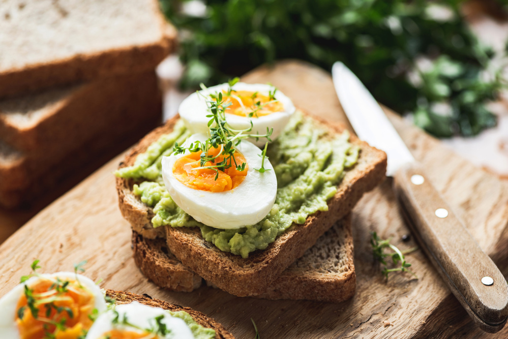 Healthy Breakfast Toast With Avocado, Boiled Egg On Wooden Cutting Board