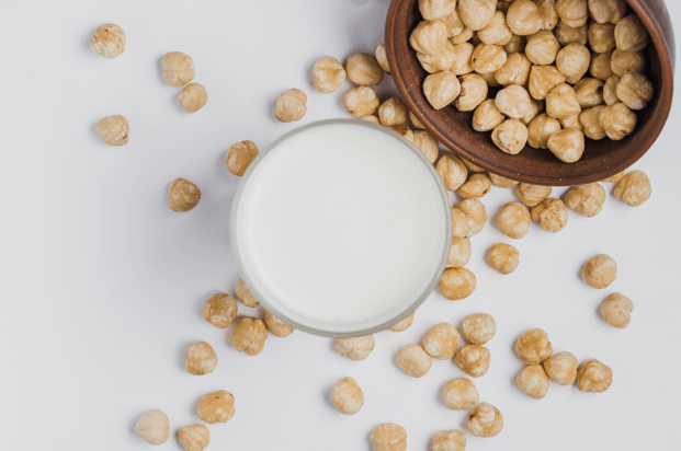 Picture-of-a-glass-of-hazelnut-milk-with-cleaned-hazelnuts-in-a-bowl-in-the-white-background
