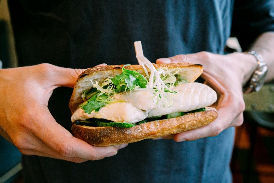 crop-adult-man-with-tasty-sandwich-with-fish-in-arms