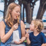 Mom and son eat fried sweet potatoes in the park.